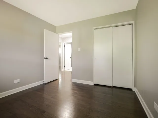 an empty room with wooden floor and closet area