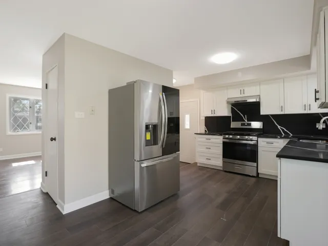 a kitchen with granite countertop a refrigerator and a stove top oven