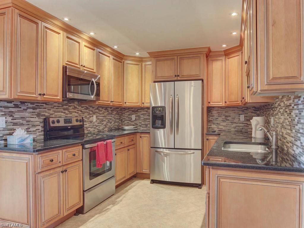 4912 Hawaii Boulevard Naples, FL 34112 - Photo 2 of 12 a kitchen with stainless steel appliances granite countertop a refrigerator sink and microwave