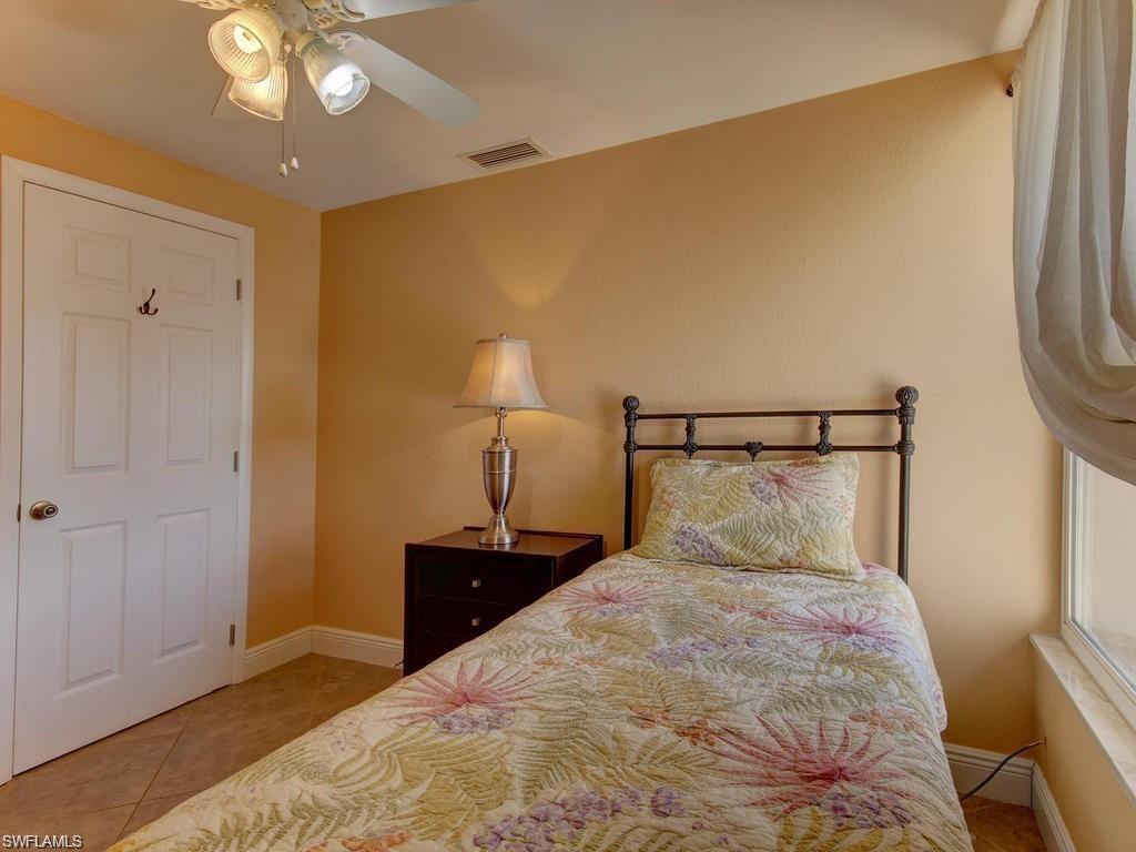 4912 Hawaii Boulevard Naples, FL 34112 - Photo 8 of 12 a bedroom with a bed and a lamp on table