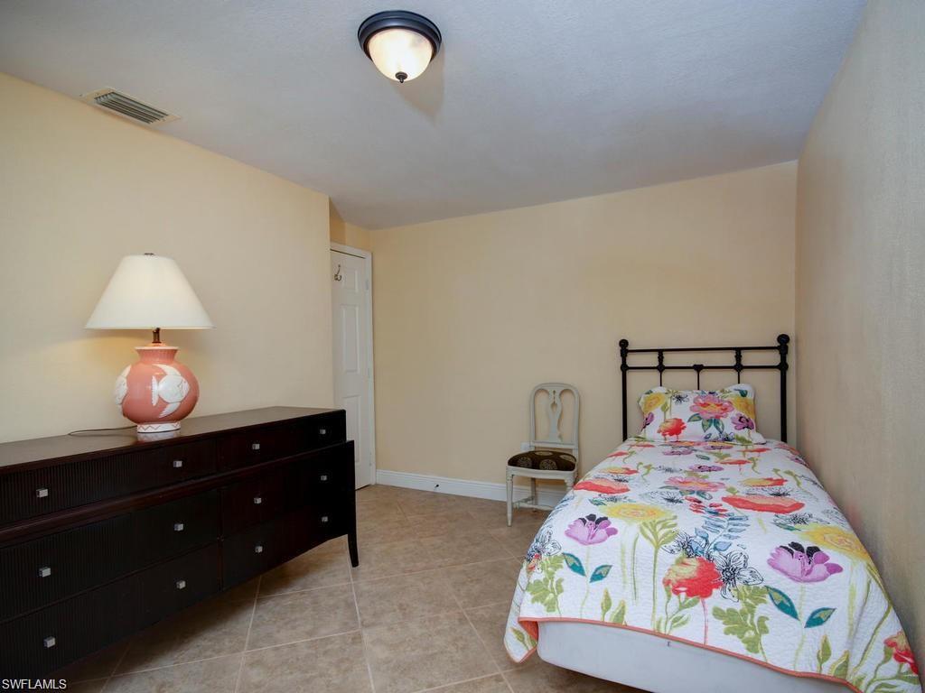 4912 Hawaii Boulevard Naples, FL 34112 - Photo 10 of 12 a bedroom with a bed and a chandelier