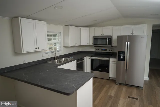 a kitchen with stainless steel appliances granite countertop a stove a refrigerator and a sink with wooden floor