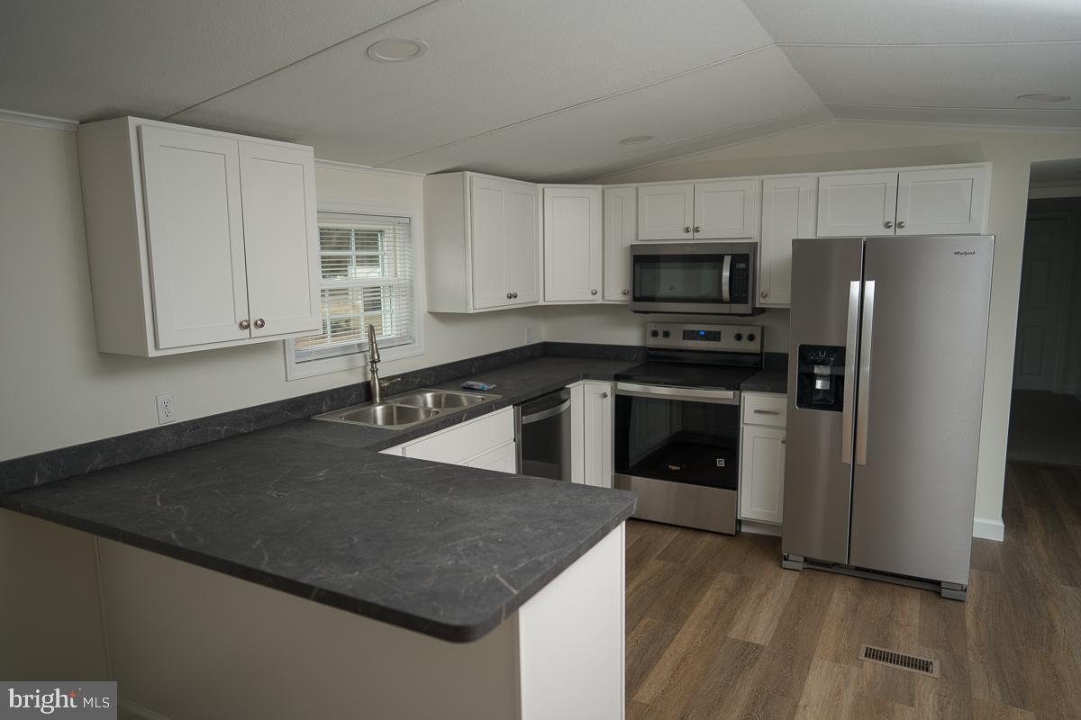 16449 Polk Road Bridgeville, DE 19933 - Photo 2 of 22 a kitchen with stainless steel appliances granite countertop a stove a refrigerator and a sink with wooden floor