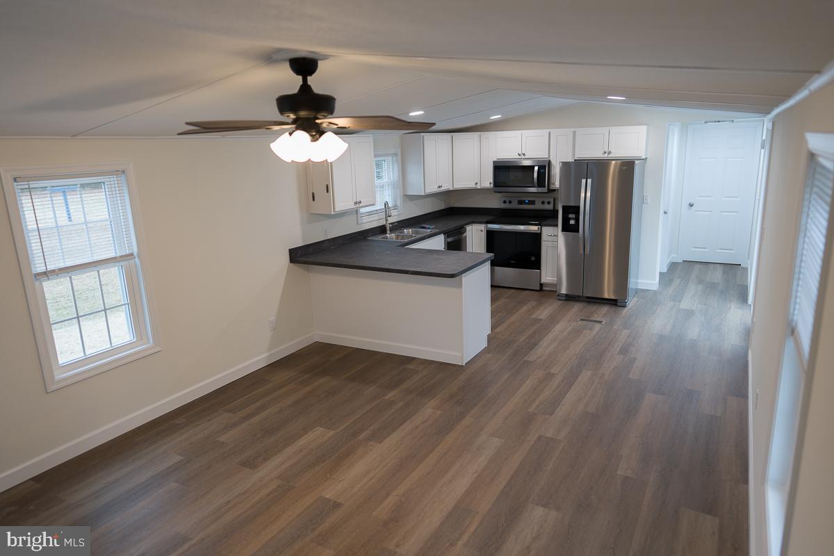 16449 Polk Road Bridgeville, DE 19933 - Photo 4 of 22 a kitchen with stainless steel appliances granite countertop a refrigerator a sink dishwasher a stove and white countertops with wooden floor