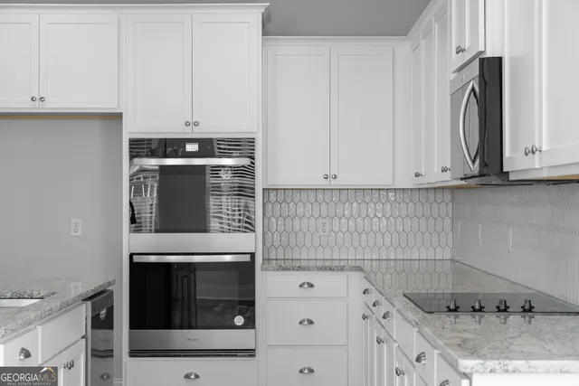 a kitchen with granite countertop white cabinets and stainless steel appliances