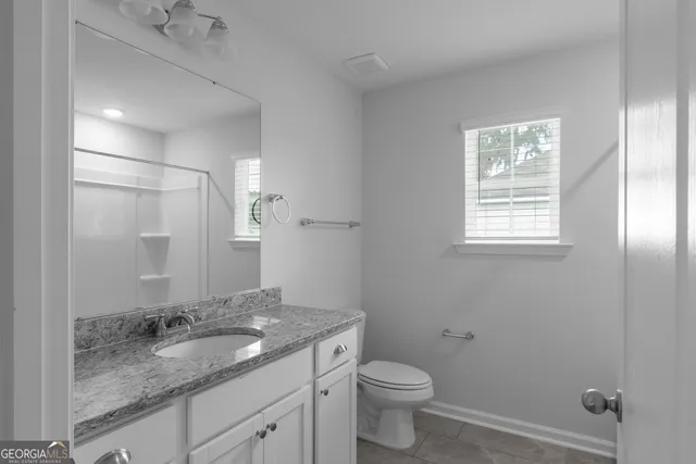 a bathroom with a granite countertop sink toilet and mirror