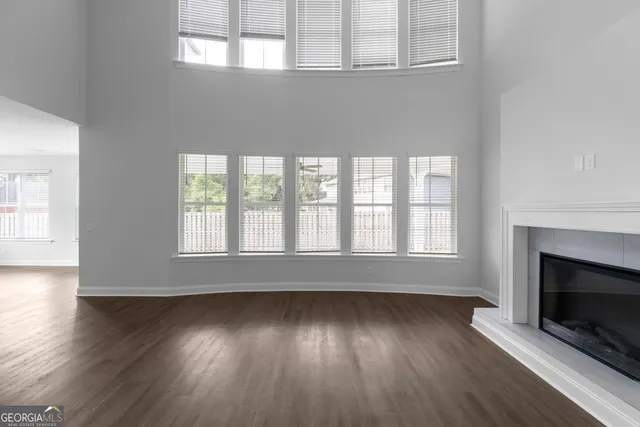 an empty room with wooden floor fireplace and windows