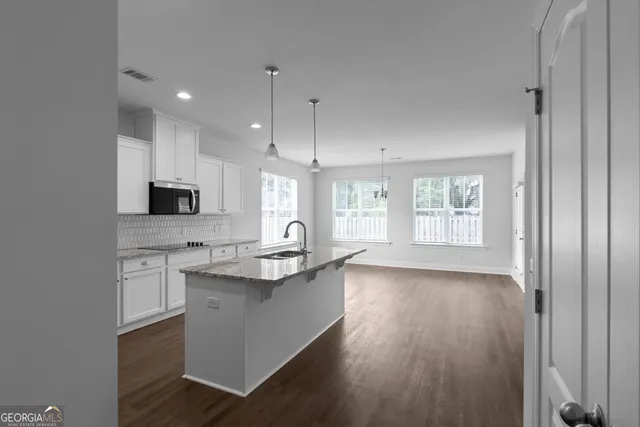a kitchen with kitchen island granite countertop a sink appliances cabinets and a counter top space