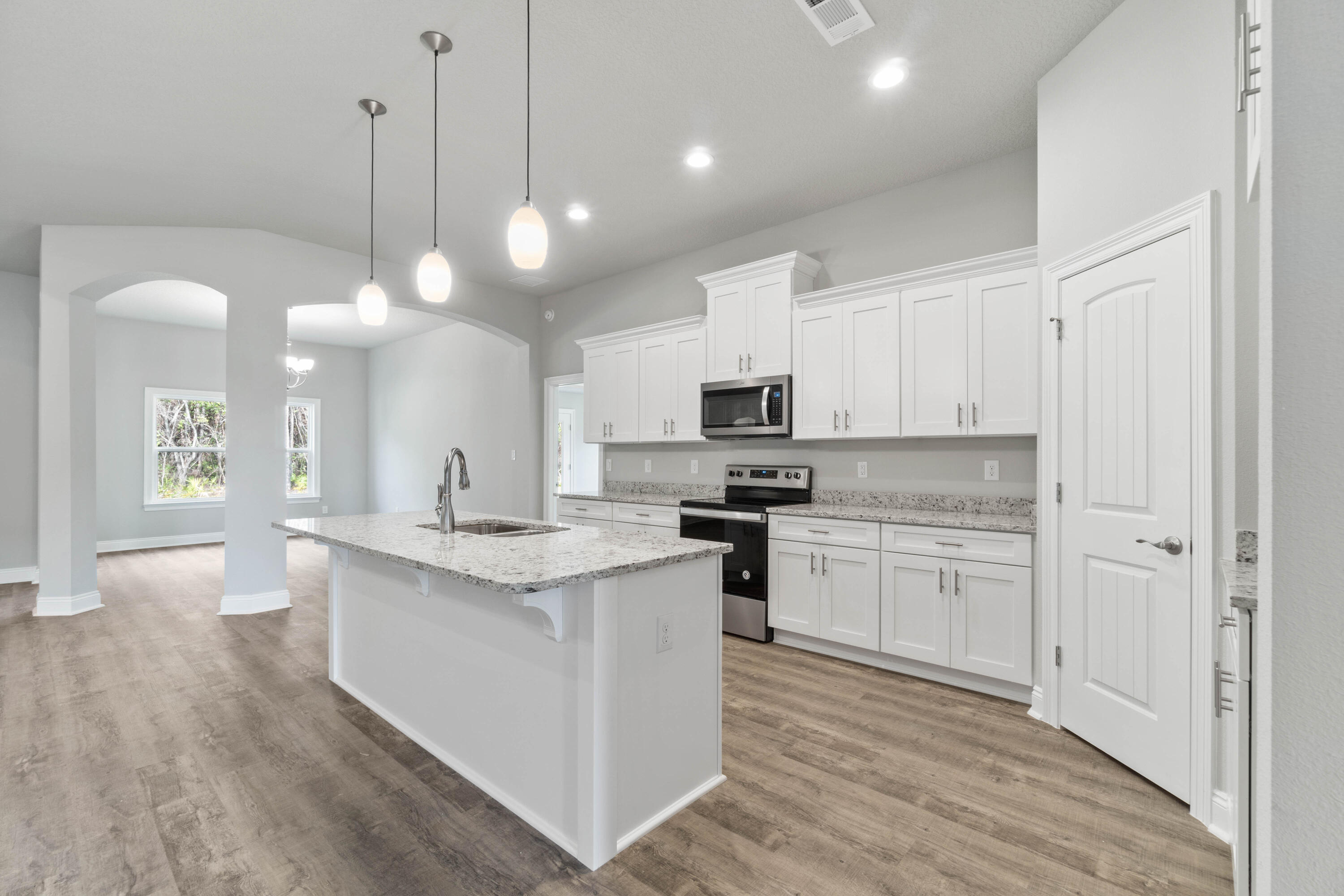 3548 Bob Tolbert Road Navarre, FL 32566 - Photo 12 of 47 a kitchen with stainless steel appliances kitchen island granite countertop a stove a sink and white cabinets with wooden floor