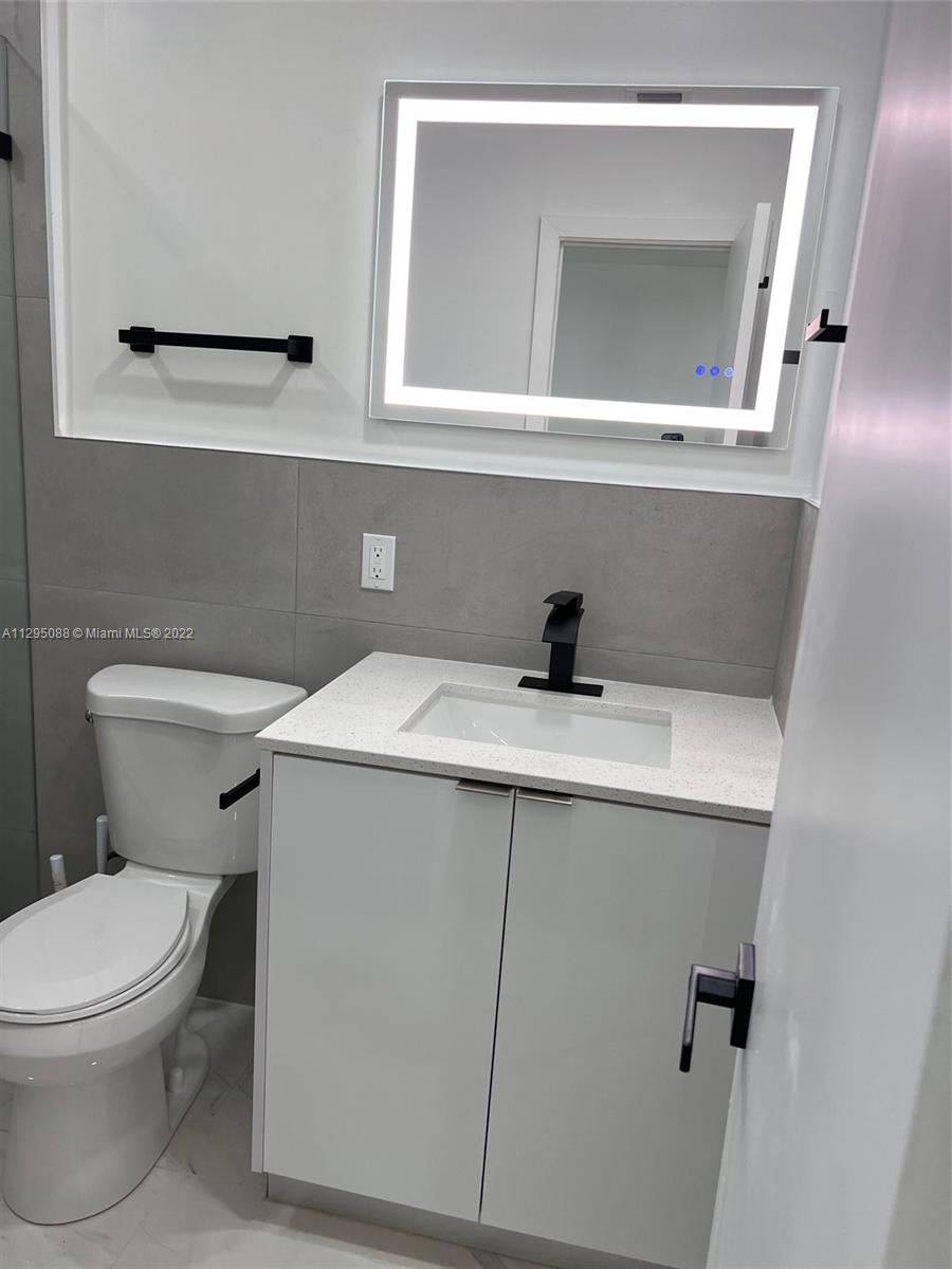 Brownsville Miami, FL 33142 - Photo 9 of 33 a bathroom with a toilet sink and mirror
