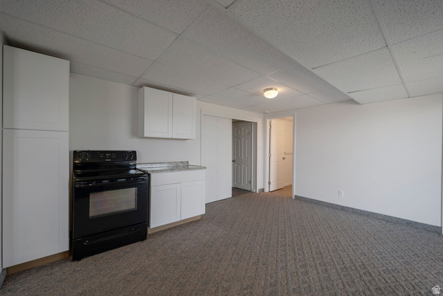 11922 Bluff View Drive Sandy, UT 84092 - Photo 24 of 30 Kitchen with black range with electric stovetop, white cabinetry, a paneled ceiling, dark carpet, and light stone countertops
