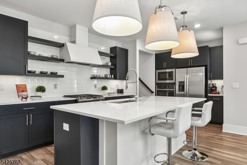 723 Station Road Dunellen, NJ 08812 - Photo 6 of 32 a kitchen with stainless steel appliances a sink a stove a dining table and chairs with wooden floor