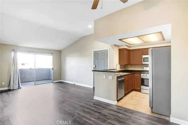 a view of kitchen with stainless steel appliances wooden floor and living room view