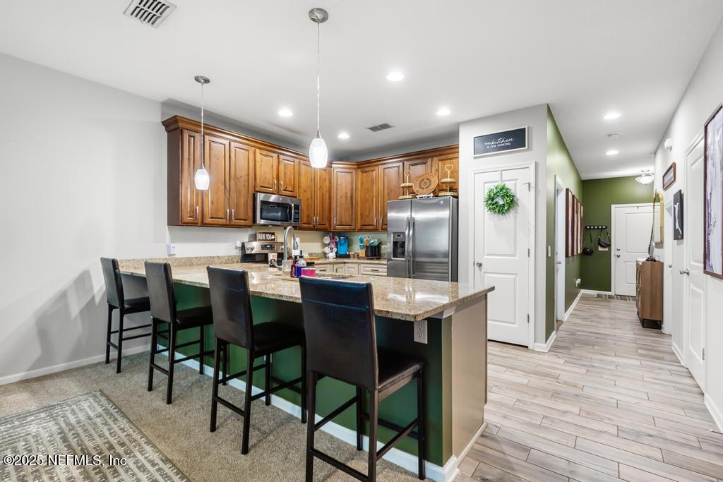 87267 Lents Road Yulee, FL 32097 - Photo 9 of 28 a kitchen with stainless steel appliances kitchen island granite countertop a table chairs and a refrigerator