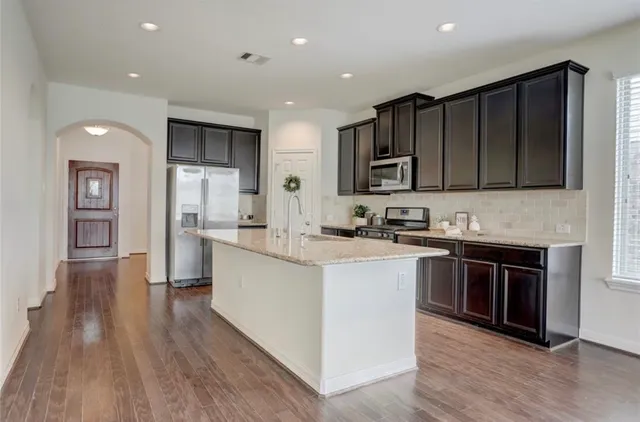 a kitchen with stainless steel appliances granite countertop wooden cabinets a stove top oven a sink and dishwasher