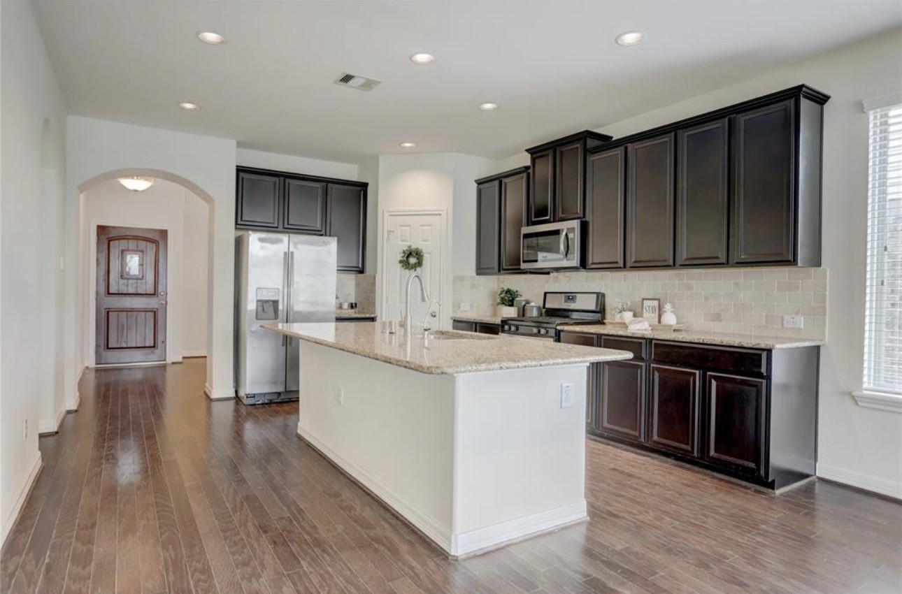 9972 Spring Rock Lane Brookshire, TX 77423 - Photo 6 of 16 a kitchen with stainless steel appliances granite countertop wooden cabinets a stove top oven a sink and dishwasher