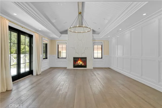 an empty room with wooden floor fireplace and windows