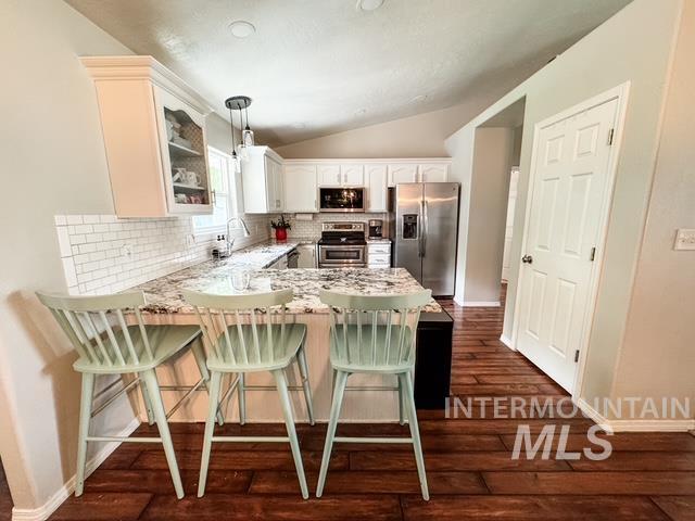808 O'Leary Way Twin Falls, ID 83301 - Photo 12 of 37 Kitchen featuring an eating bar with stone-finish countertops, stainless steel appliances, white subway tile backsplash, white cabinetry, and wood-finish flooring