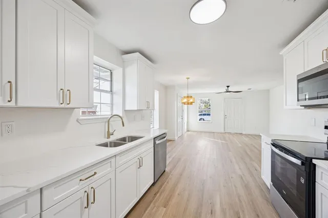 a view of a kitchen counter space with stainless steel appliances wooden floor and cabinets