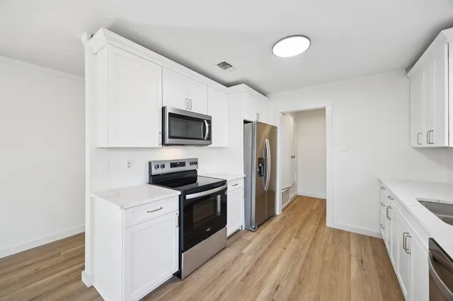 a kitchen with a sink wooden floor and stainless steel appliances