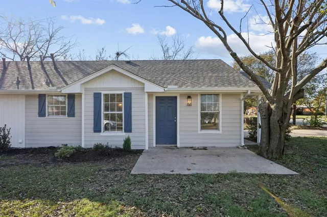 a front view of a house with a yard and a tree
