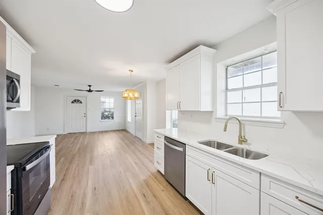 a kitchen with granite countertop a sink cabinets stainless steel appliances and a window