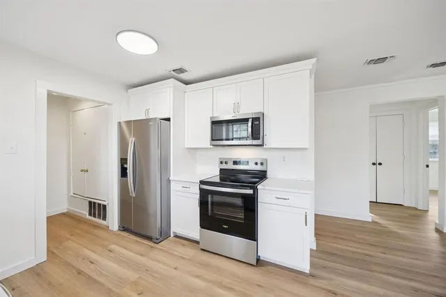 a kitchen with stainless steel appliances white cabinets and wooden floor