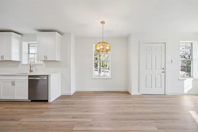 a view of an empty room with window and wooden floor