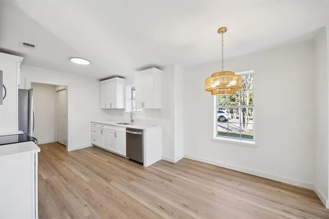 a kitchen with stainless steel appliances granite countertop a sink a refrigerator and a wooden floor