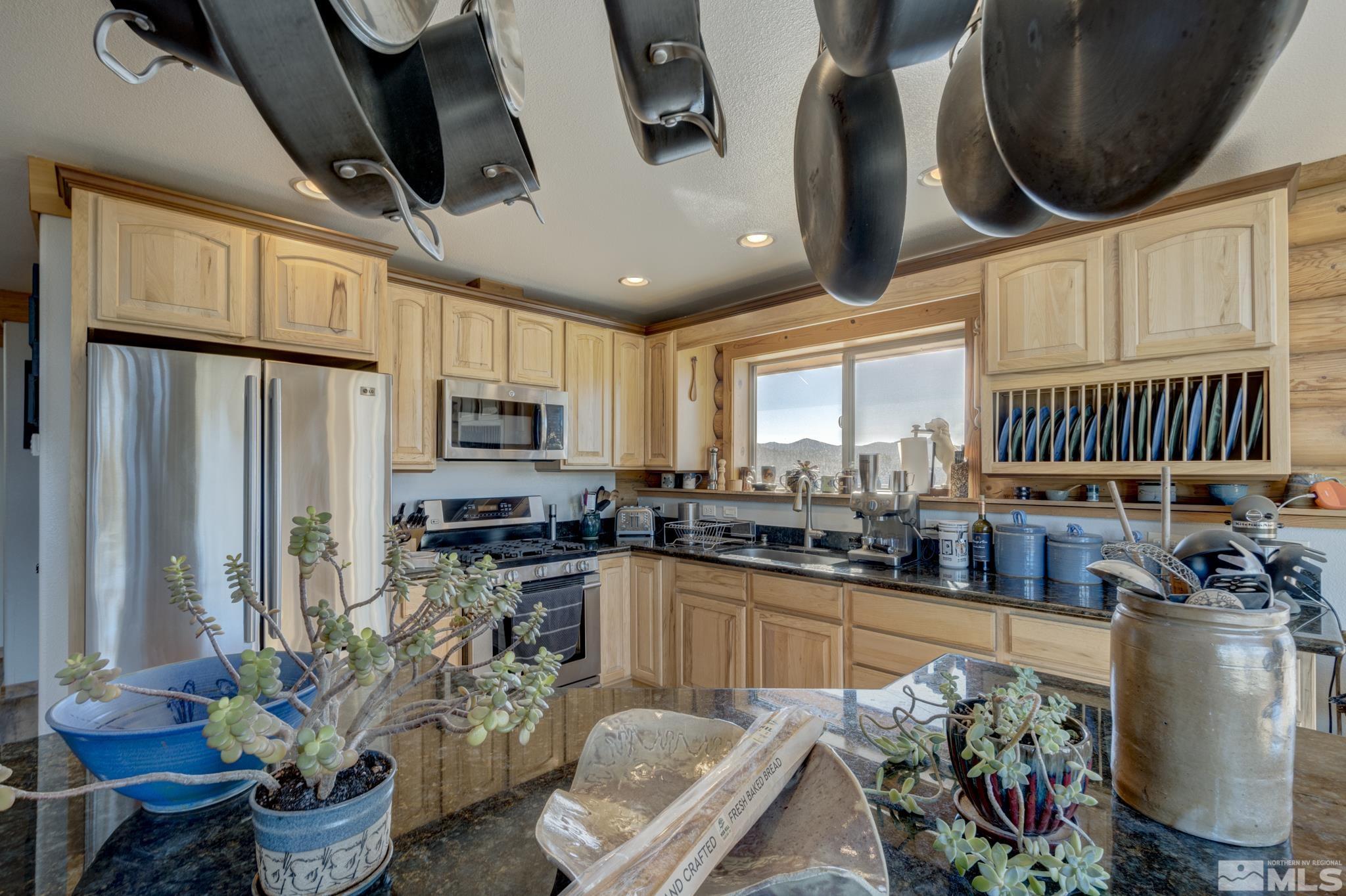 2740 Goldfield Road Reno, NV 89521 - Photo 15 of 39 a kitchen with stainless steel appliances a stove a sink dishwasher a dining table and chairs with wooden floor