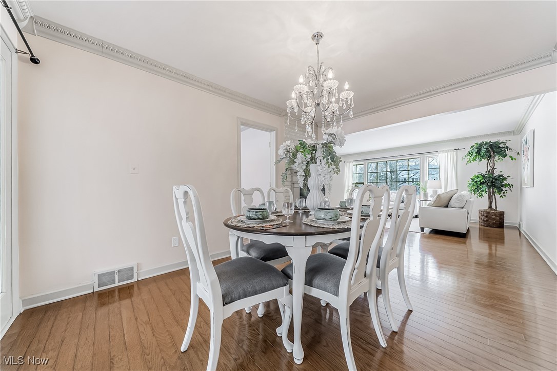 Dining space featuring ornamental molding, a chandelier, and wood flooring