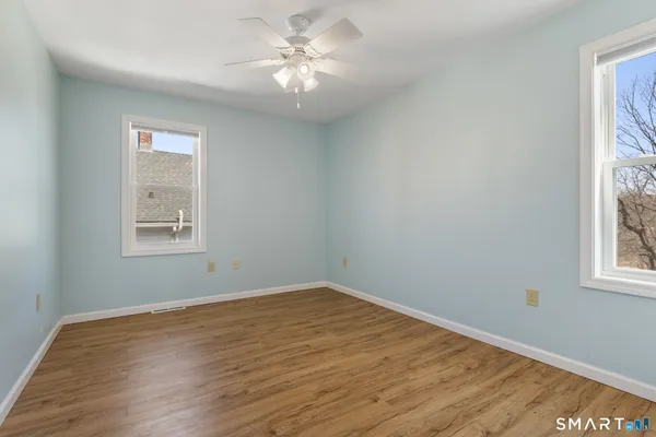 a view of empty room with wooden floor and fan