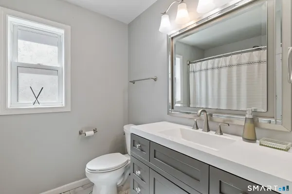 a bathroom with a toilet a sink a mirror a and a window