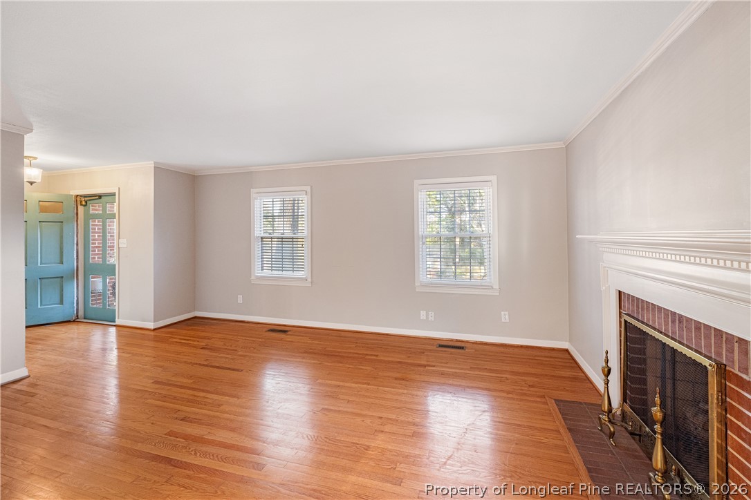 2527 Huntington Road Fayetteville, NC 28303 - Photo 6 of 39 an empty room with wooden floor fireplace and windows