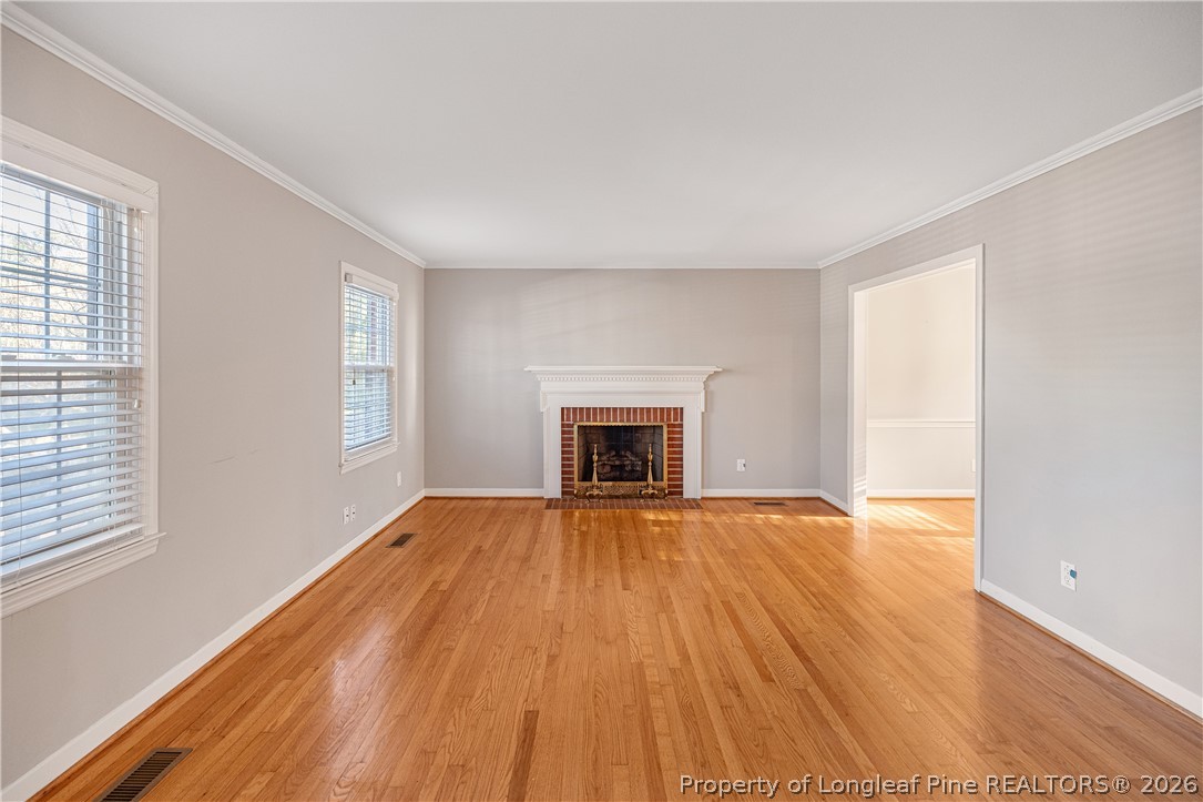 2527 Huntington Road Fayetteville, NC 28303 - Photo 7 of 39 an empty room with wooden floor and fireplace