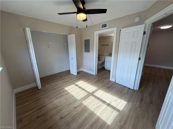 a view of empty room with wooden floor and fan