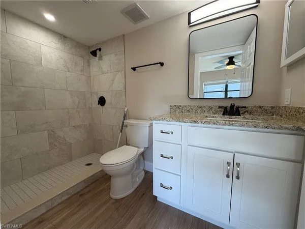 a bathroom with a granite countertop toilet sink and mirror