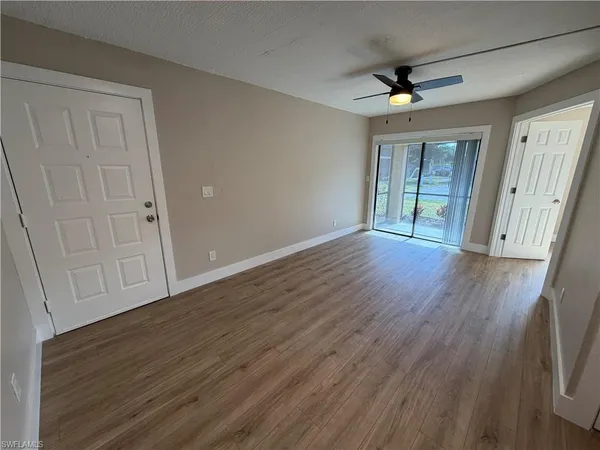 a view of an empty room with wooden floor and a window