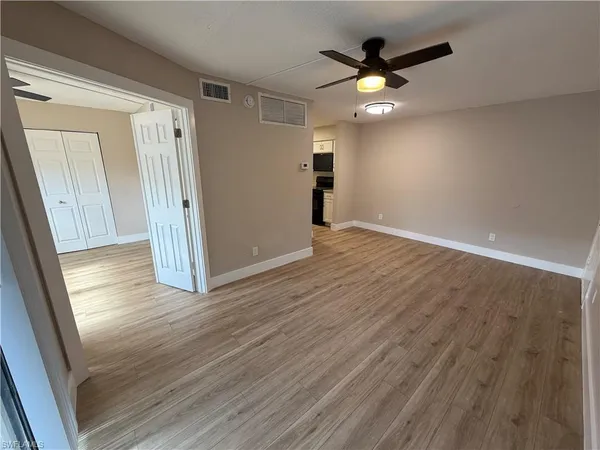 a view of an empty room and wooden floor and cabinet