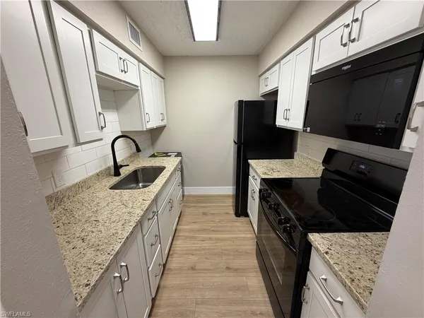 a kitchen with stainless steel appliances kitchen island granite countertop a sink and a stove top oven with wooden floor