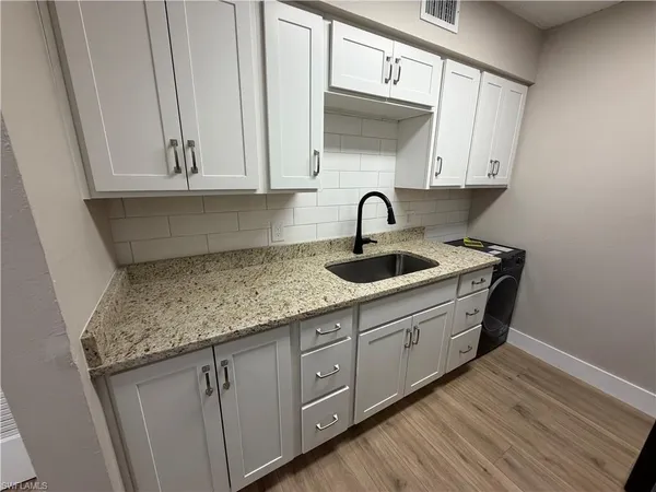 a kitchen with stainless steel appliances granite countertop a sink dishwasher and cabinets with wooden floor