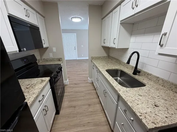a kitchen with granite countertop a sink a stove and cabinets