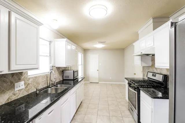 a kitchen with granite countertop a stove and a sink