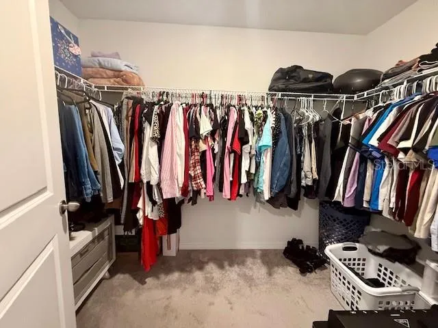 a view of walk in closet with clothes and shoes