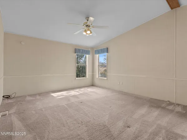 en empty room with windows and chandelier fan