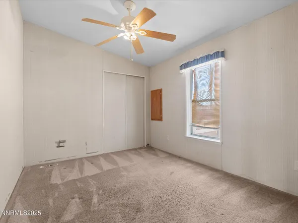 an empty room with windows and fan