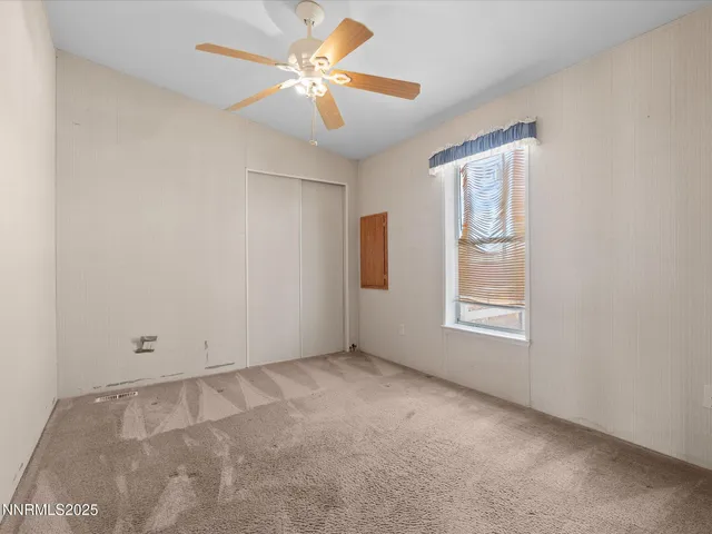 an empty room with windows and fan