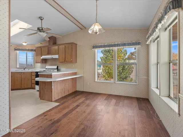 a kitchen with stainless steel appliances granite countertop a stove a sink dishwasher a refrigerator and a large window with wooden floor