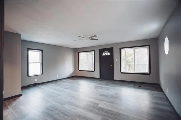 an empty room with wooden floor and windows