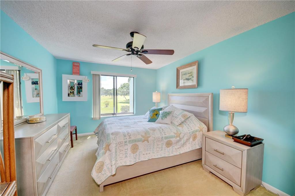 5433 Southeast Miles Grant Road, Unit E203 Stuart, FL 34997 - Photo 16 of 42 a bedroom with a bed and a chandelier